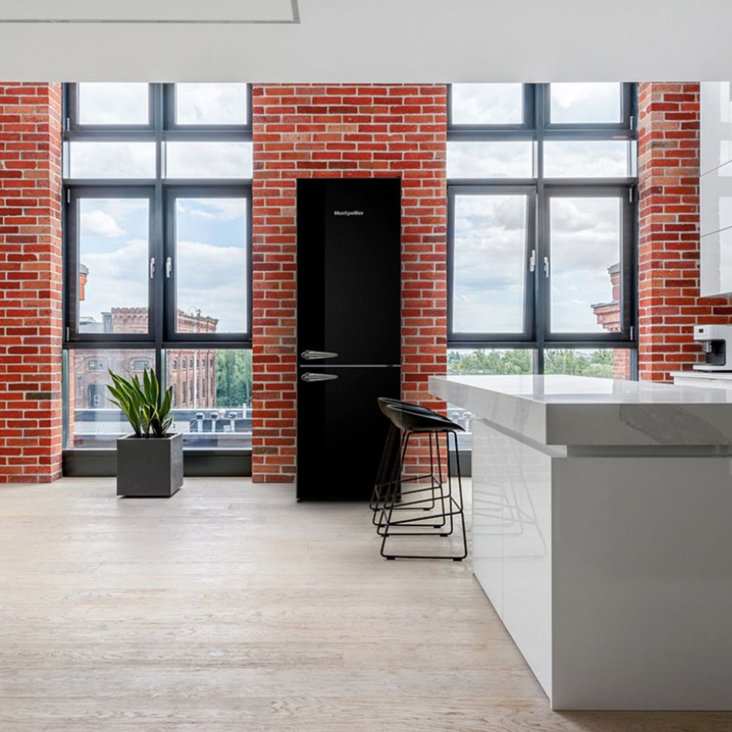 Modern kitchen with black refrigerator, white island, and brick walls.